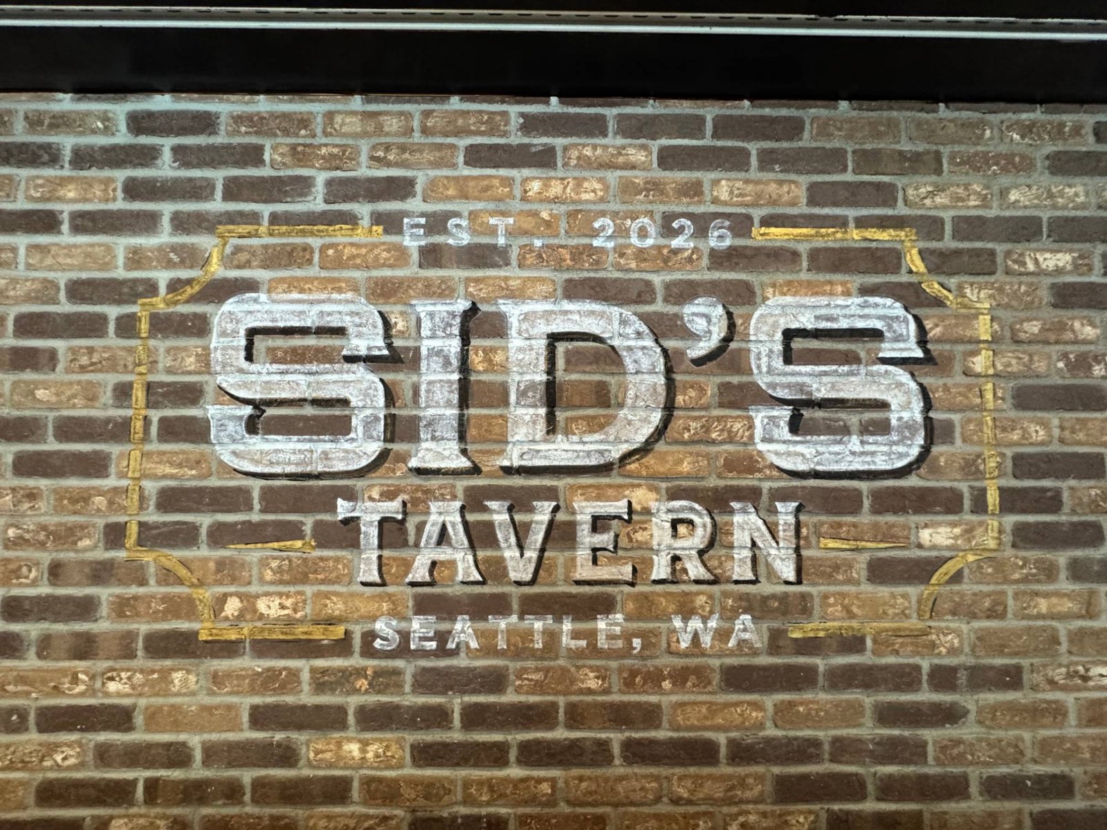 Hand painted Sid's Tavern sign on the brick wall inside the bar, established 2026, Seattle, WA